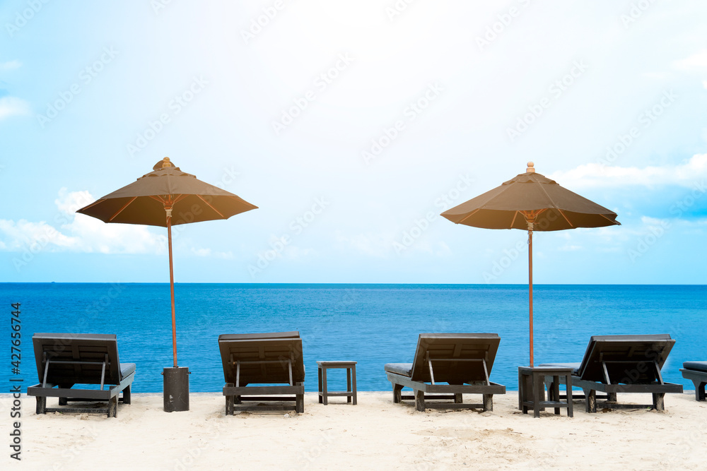 Sunbed with umbrella lined up facing the turquoise sea. With the atmosphere of the hot sunshine in summer.