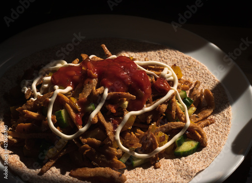 Vegan Greek Kebab with yellow peppers, red onions and cucumber dressed with salsa and mayonnaise on a large tortilla