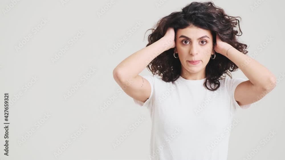The confused woman not knowing what to do shrugging shoulders and spreading her arms to the side while standing in the studio The confused woman not knowing what to do shrugging shoulders and spreading her arms to the side while standing in the studio