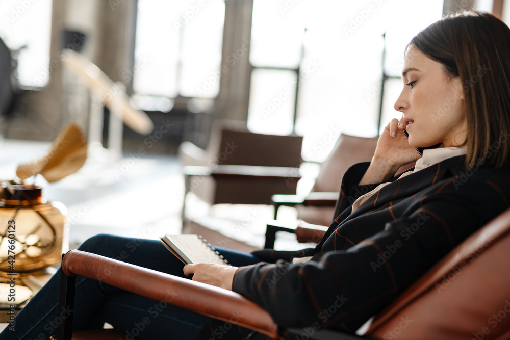 Mid aged business woman in jacket talking on mobile phone