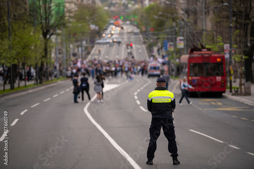 Police officer stand guard, stops traffic and blocking city street during protests against coronavirus-covid19 measures and city lockdown, in Belgrade city, Serbia.
