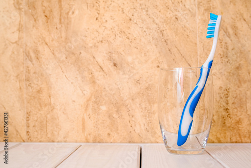 Toothbrush stands in a glass on a beige background 
