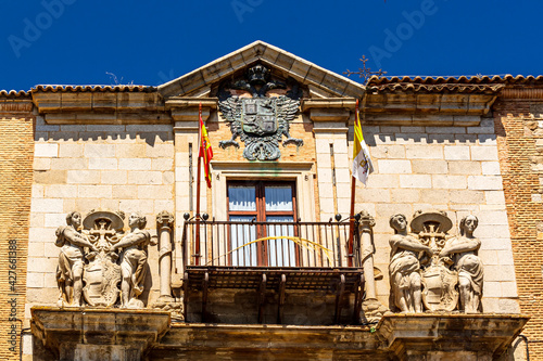 The pediment of the Bishop's Palace with the coat of arms and flags. Toledo, Castilla La Manch, Spain.