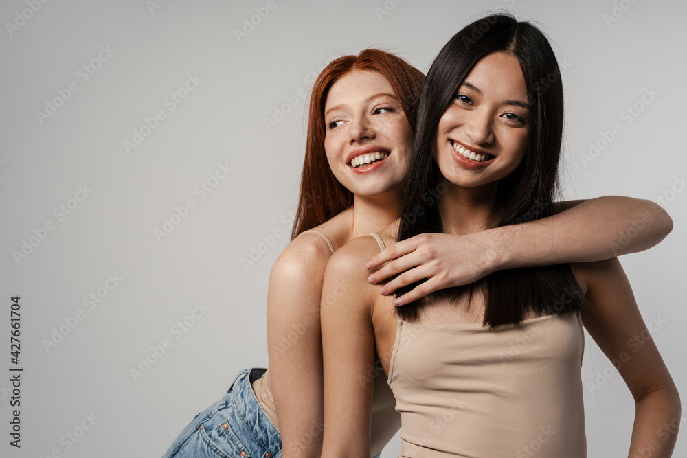 Multiracial two women hugging and laughing at camera Multiracial two women hugging and laughing at camera