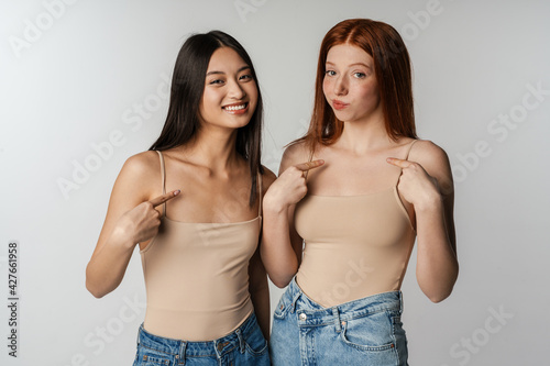 Multiracial two women smiling and pointing finger at themselves
