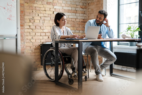 Multiracial young two colleagues smiling while working with laptop