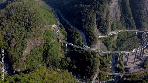 Aerial tilt up from a huge and busy bridge to a pristine mountain range. Viaduct Égratz de Passy, french Alps and Montblanc range, highest mountain in Europe. Autumn colors.