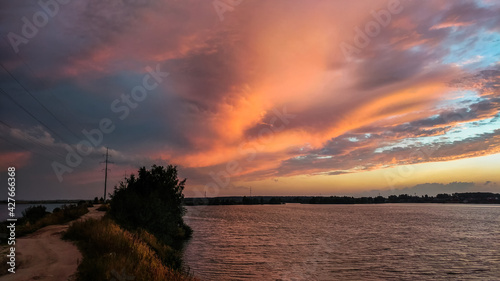 Obraz na płótnie Sunset over the lake with beautiful clouds illuminated by the rays of the setting sun w salonie