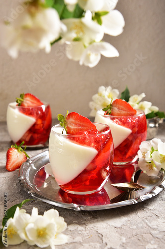 Two-color jelly of strawberries and cream in a beautiful glass, in a spring composition.
