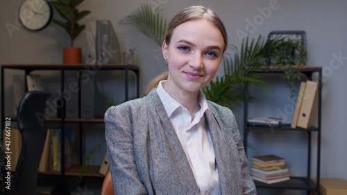 Joyful girl entrepreneur freelancer concentrated developing new project while looking at camera. Young businesswoman boss working in modern office interior. Portrait of positive woman co-worker photo