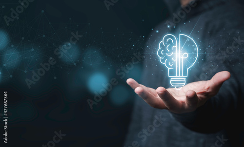 Businessman holding half of virtual lightbulb and brain on blue bokeh background , Smart thinking idea and inspiration innovation concept. photo
