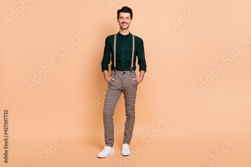 Full size photo of handsome smiling cheerful confident businessman hold hands pockets isolated on pastel color background