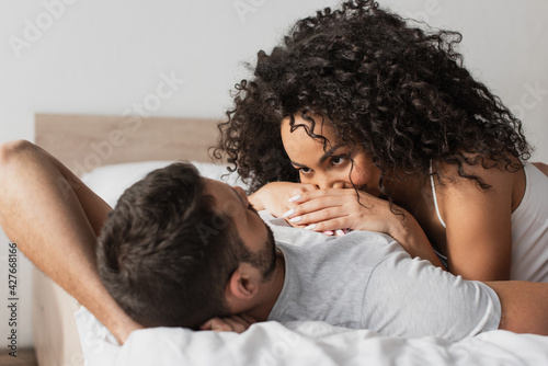 interracial couple lying together on bed at home