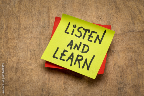 listen and learn reminder - motivation words on a sticky note against handmade paper, learning and communication concept