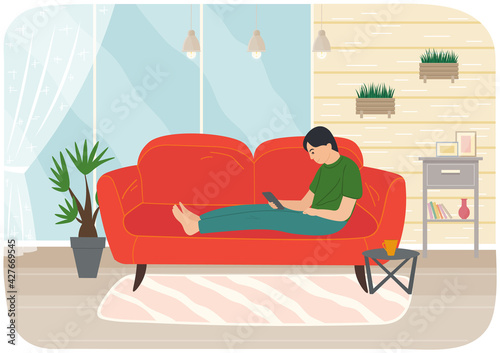 Young man sitting on couch with tablet, studying remotely, watches social media, serfing Internet