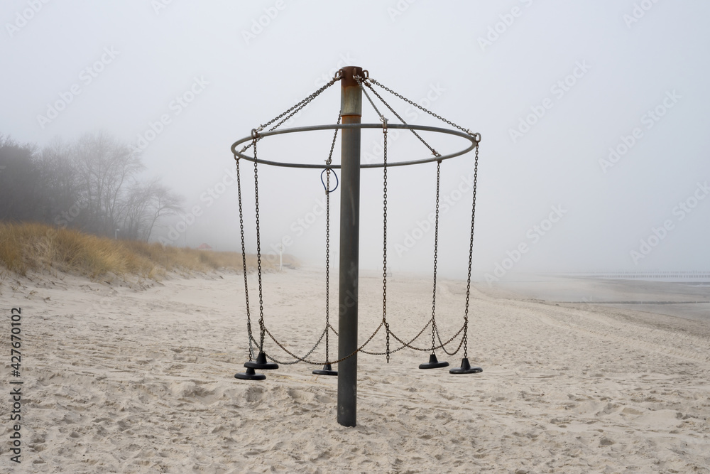 empty and broken swing on the beach with sea fog, corona lockdown, loneliness, alone, where are the kids empty and broken swing on the beach with sea fog, corona lockdown, loneliness, alone, where are the kids