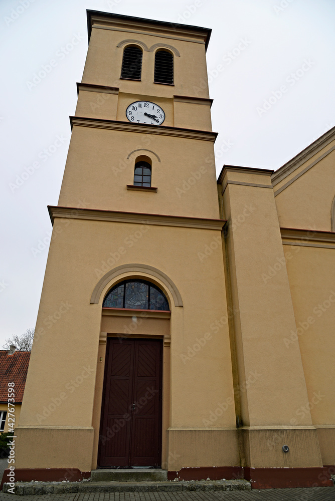 The belfry erected at the beginning of the 20th century and the close-up of the windows and the cross of the Catholic church of of Saint Anthony of Padua in the town of Gąski in Masuria in Poland