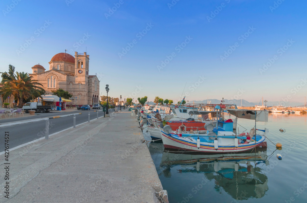 Fototapeta premium Port of charming Aegina town with yachts and fishermen boats docked in Aegina island, Saronic gulf, Greece, at sunset.