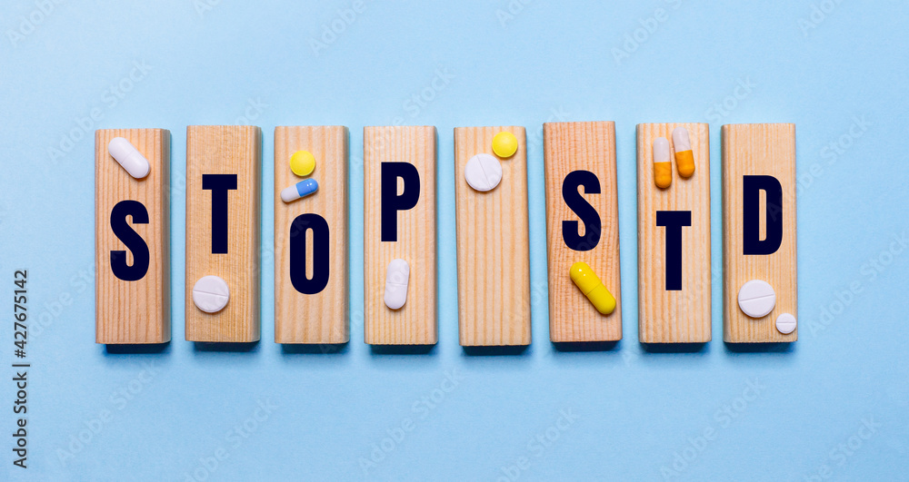 The STOP STD is written on wooden blocks on a light blue table near the pills. Medical concept The STOP STD is written on wooden blocks on a light blue table near the pills. Medical concept