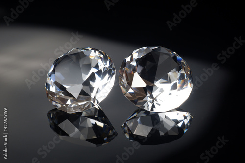 Couple of wonderful pure diamonds with reflections on black mirror background close up view. Jewelry diamonds sale  invitation  action  discount banner  poster  card template with copy space