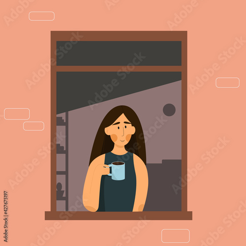Girl with dark hair in the window isolated at home holds a cup with a drink. 