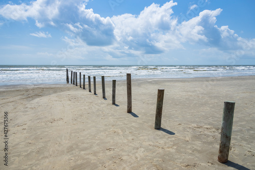 Poles in the beach with ocean and blue sky background  © Martina