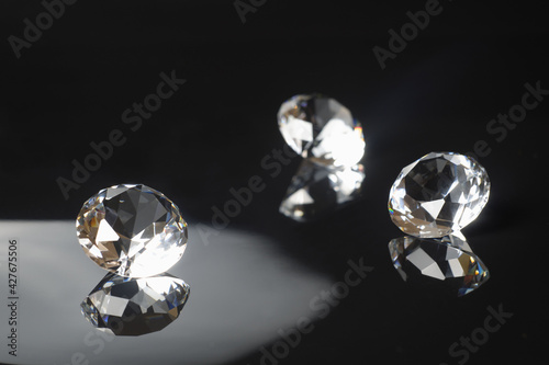 Three excellent pure diamonds with reflection on black mirror background close up view selective focus. Jewelry diamonds sale  invitation  action  discount banner  poster  card template