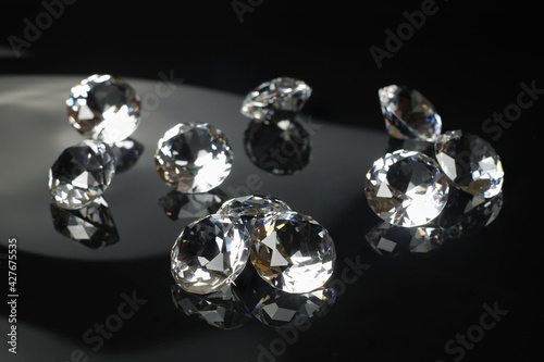 Several excellent pure diamonds with reflection on black mirror background close up view selective focus. Jewelry diamonds sale, invitation, action, discount banner, poster, card template