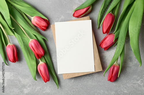 Fototapeta Naklejka Na Ścianę i Meble -  Greeting card with fresh red tulip flowers on grey concrete background