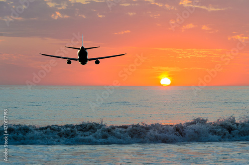 Sunset or sunrise (dawn, dusk ) flight of the airplane (jet) over beautiful sky and ocean. © karamysh