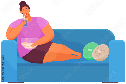 Fat woman is watching television while sitting on her couch and eating snack, drinking fizzy drink