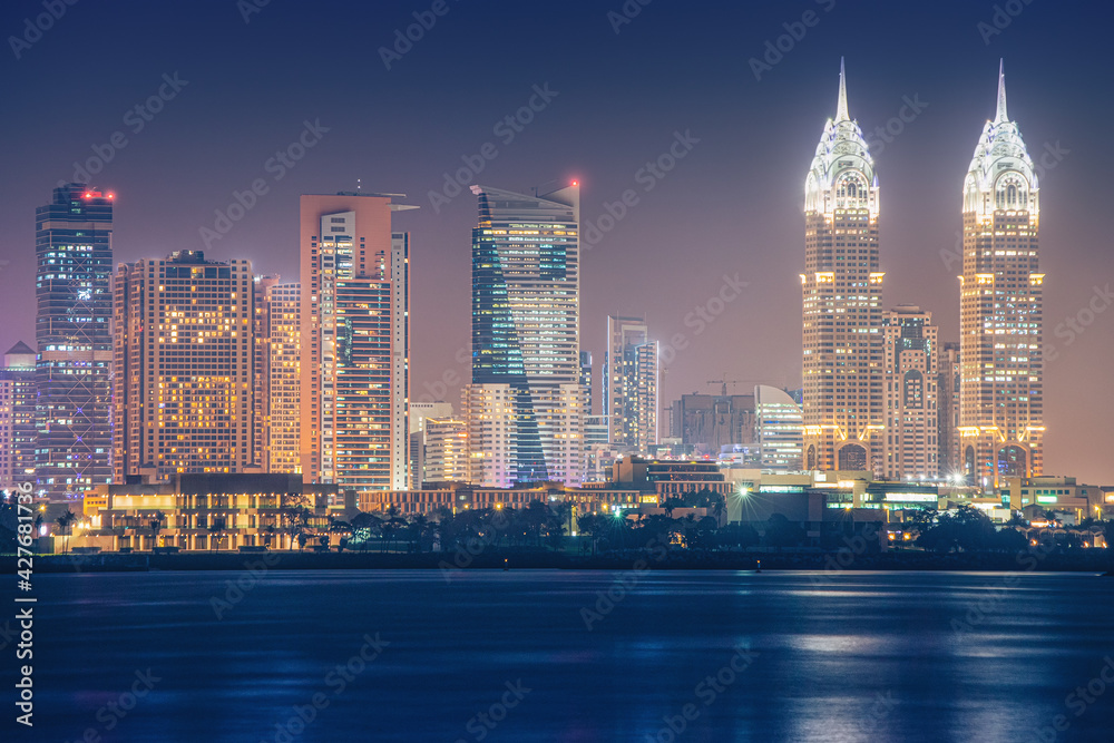 Night sea view of the brightly lit Internet City area in Dubai. Concept of real estate investment and the cost of electricity for lighting Night sea view of the brightly lit Internet City area in Dubai. Concept of real estate investment and the cost of electricity for lighting