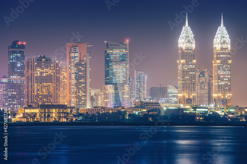 Night sea view of the brightly lit Internet City area in Dubai. Concept of real estate investment and the cost of electricity for lighting