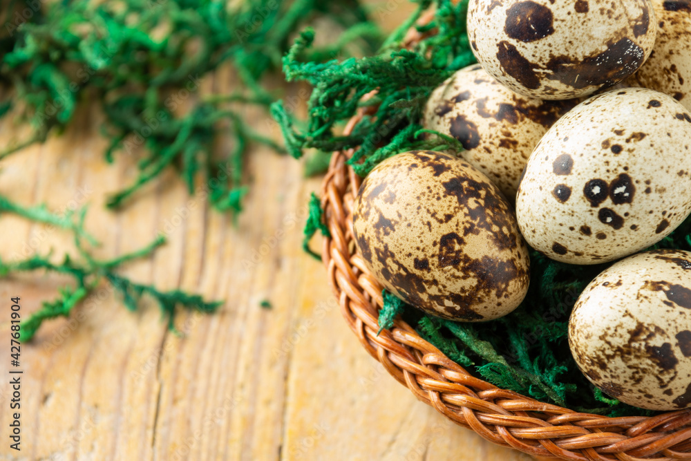 Obraz premium Aerial view of basket with quail eggs on wooden table with green grass, selective focus, horizontal, with copy space