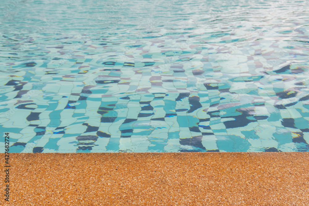 Close up with copy space of beautiful swimming pool with rock rim and blue clear water ripples shows vacation destination for summer holiday under sunlight, beach and water reflection.