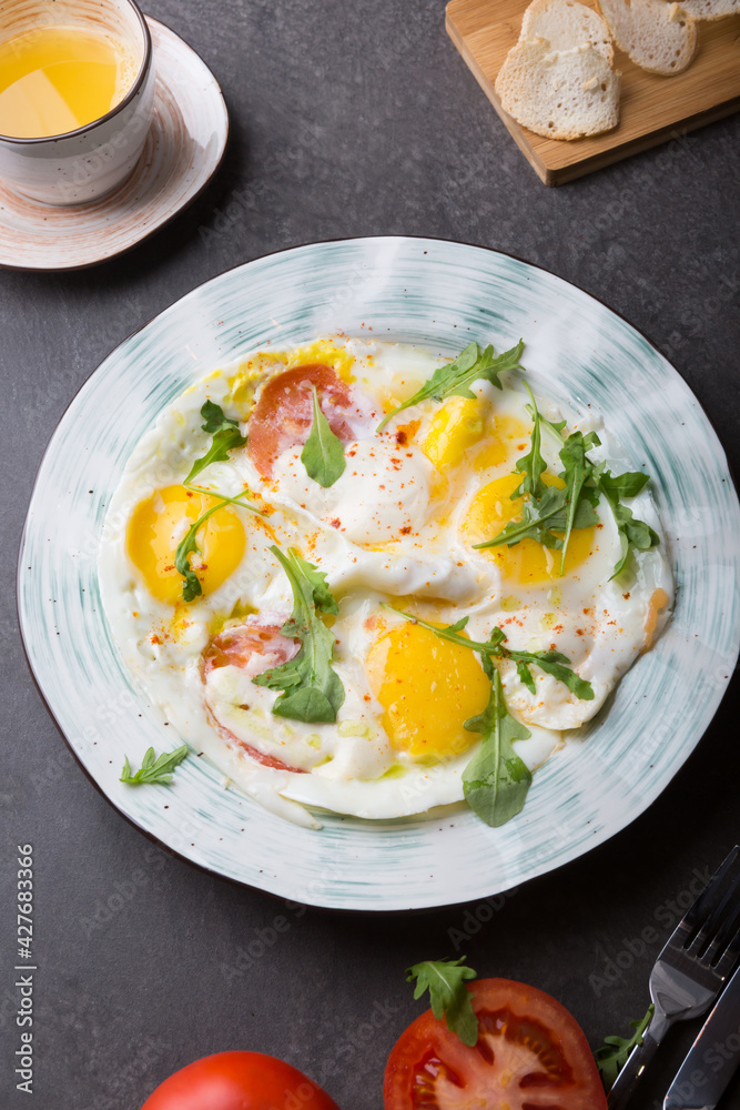 Fried eggs with tomatoes and herbs served for breakfast