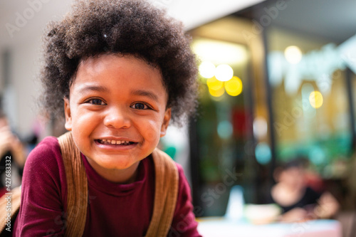 Portrait of playful black kid smiling and making funny face, African American boy with afro hair looking at camera