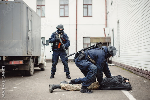 Obraz na plátně Two police officers with machine guns apprehend the perpetrator