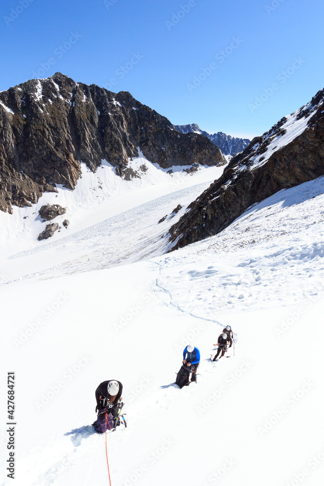 Rope team having a break on glacier Sexegertenferner and mountain snow panorama with blue sky in Tyrol Alps, Austria