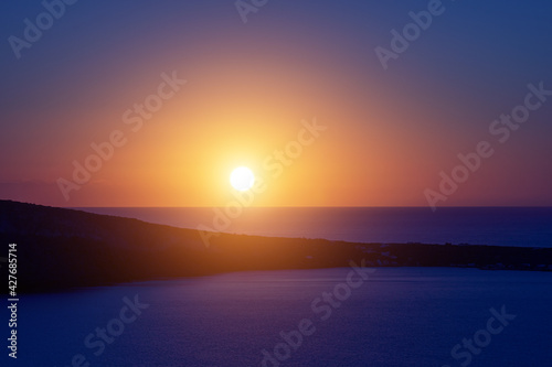 The sun sets over the sea horizon. Sunset on the sea against the backdrop of the island