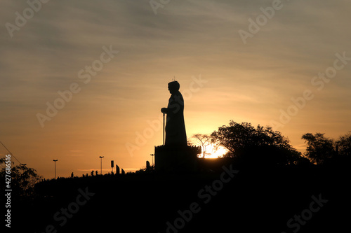 Silhouette of the Statue of Priest Cícero and some trees around it, on Horto hill, at sunset.