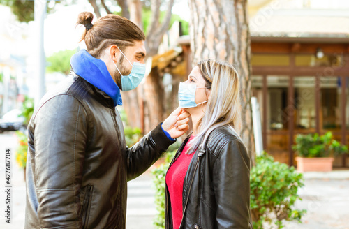happy group of a caucasian man and a blonde woman wearing protective face mask after lockdown reopening. Young couple in a romantic sweet moment outdoor in winter. girl and a boy. new normal lifestyle