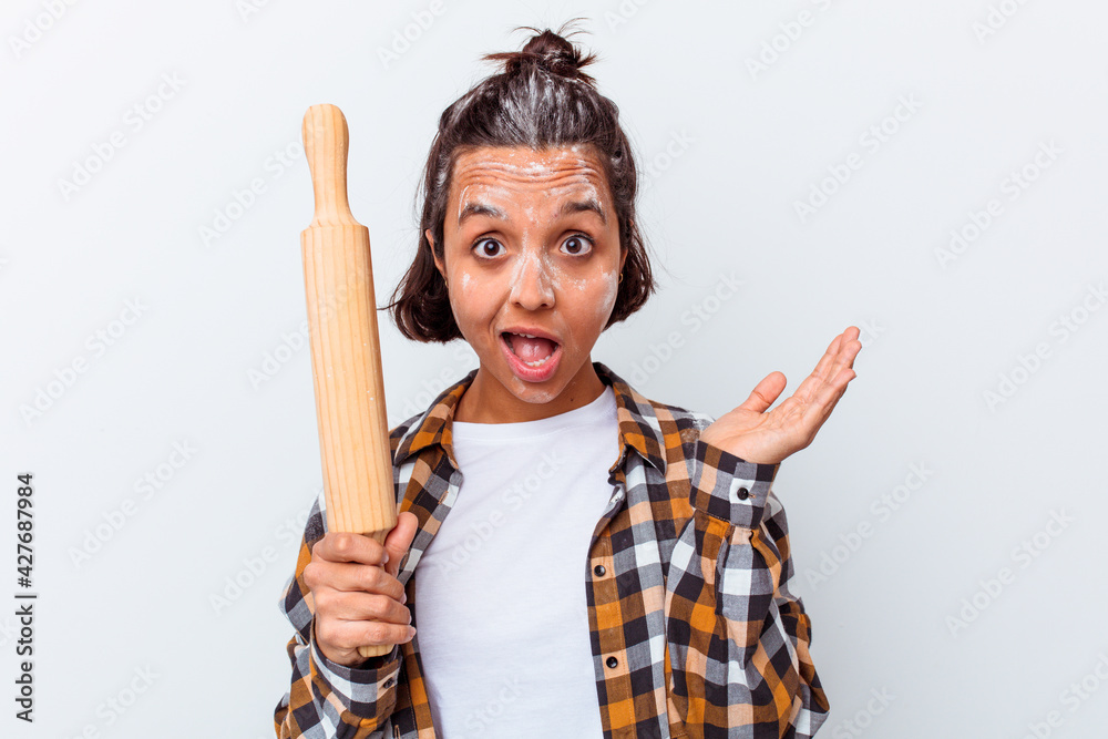 Young mixed race woman making bread isolated on white background surprised and shocked. Young mixed race woman making bread isolated on white background surprised and shocked.