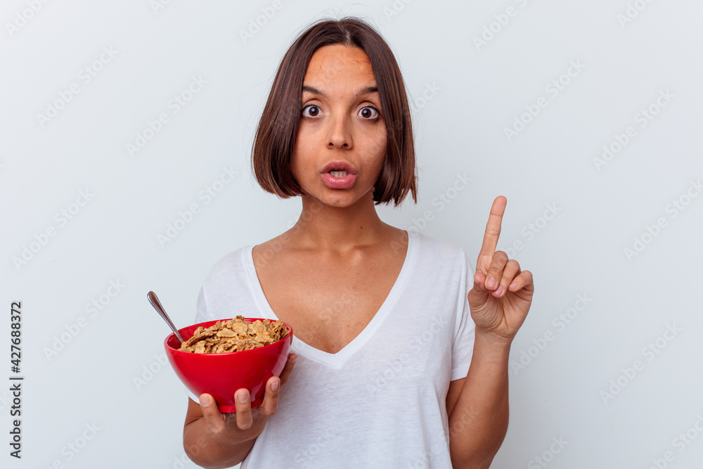 Young mixed race woman eating cereals isolated on white background having some great idea, concept of creativity. Young mixed race woman eating cereals isolated on white background having some great idea, concept of creativity.