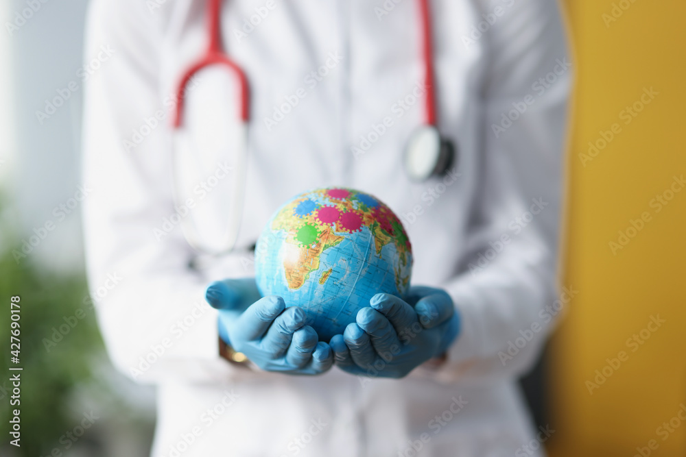 Doctor in protective gloves holding globe with viruses closeup Doctor in protective gloves holding globe with viruses closeup