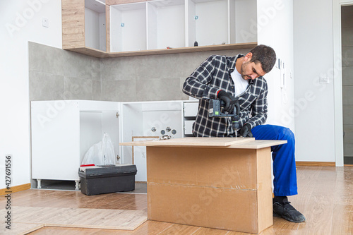 The carpenter finalizing the assembly of the kitchen shelf