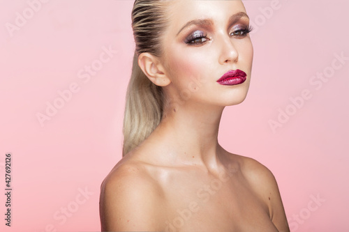 Close-up portrait of beautiful young woman with perfect makeup. Closed eyes model, with hair straightened posing on pink background.