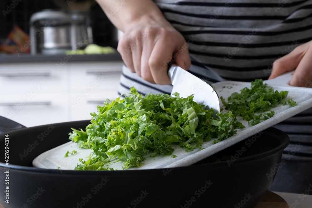 Woman is cutting kale cabbage on the kitchen Woman is cutting kale cabbage on the kitchen
