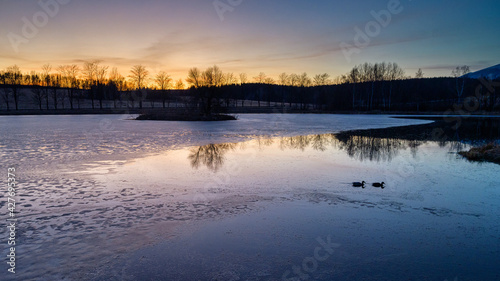 frozen pond with an island in the middle at sunset  golden hour