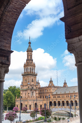 Spanish Square, in the center of Seville. Very touristic travel destination empty due to coronavirus measures. View of the south tower. Coloured flowers, blue sky with few clouds. 